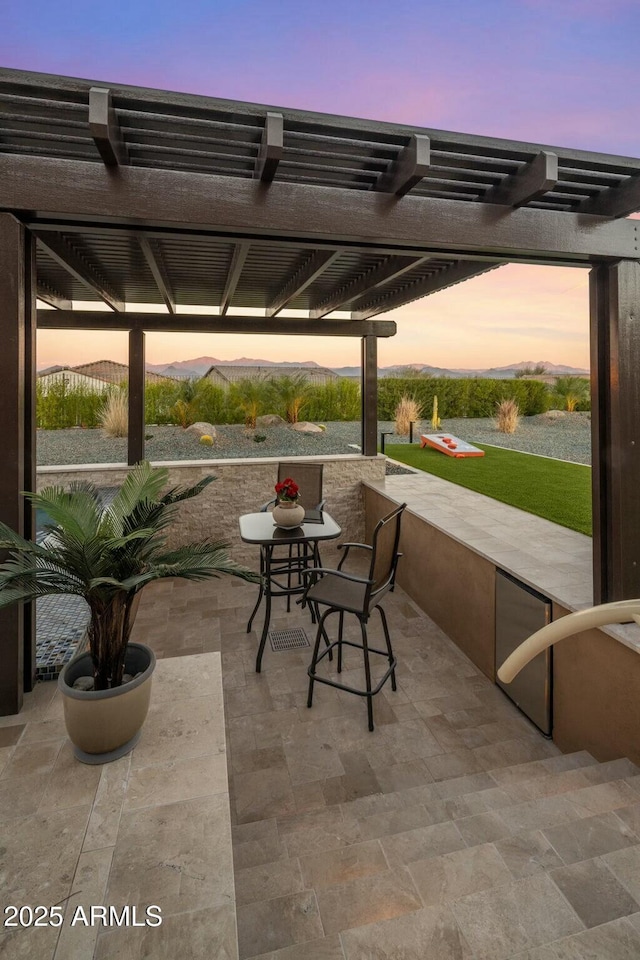 patio terrace at dusk featuring a pergola and a mountain view