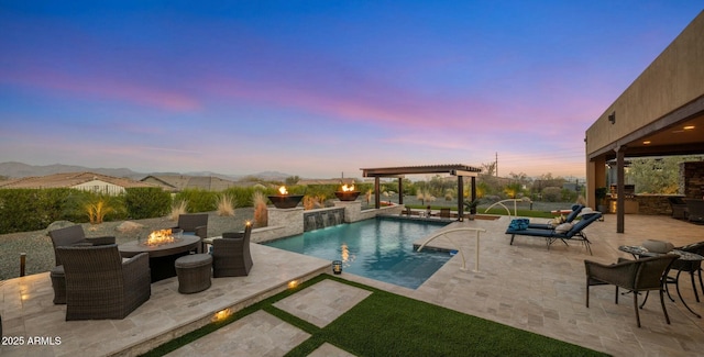 pool at dusk featuring pool water feature, a mountain view, a patio area, and exterior kitchen