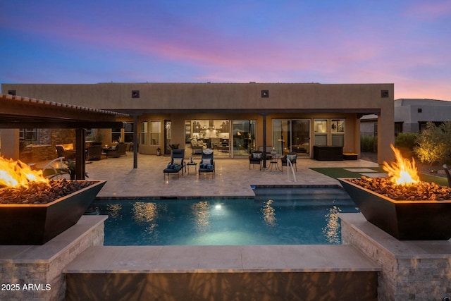 pool at dusk with a patio area and an outdoor living space with a fire pit