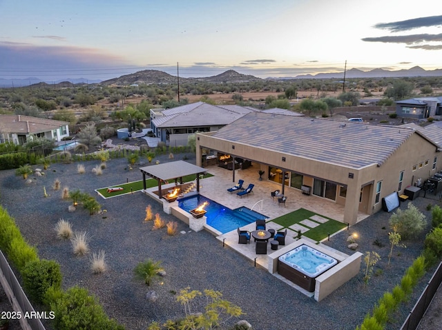 exterior space with a mountain view, a patio, and an outdoor living space with a fire pit