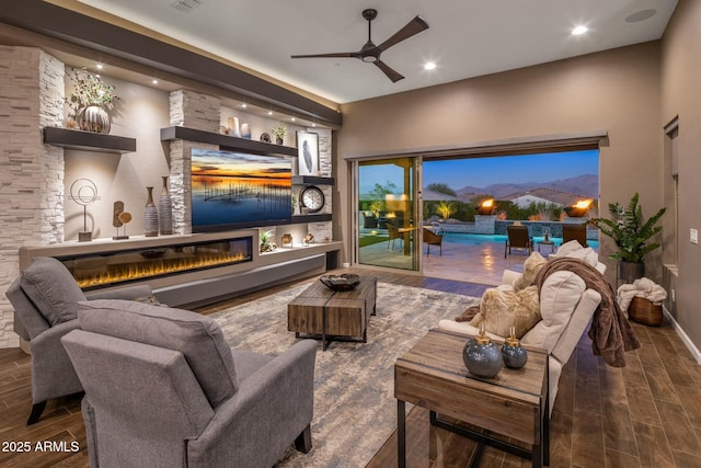 living room with built in shelves, a large fireplace, and ceiling fan