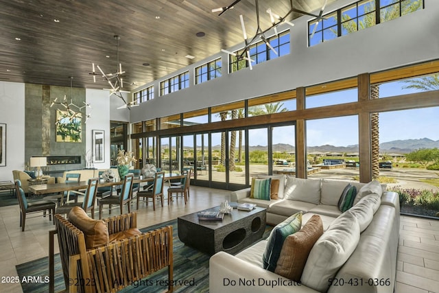 living room featuring a wealth of natural light, a mountain view, a towering ceiling, and wood ceiling