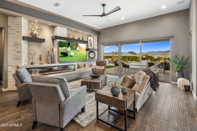 living room featuring a stone fireplace and ceiling fan