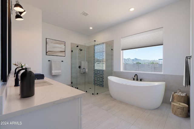 bathroom featuring shower with separate bathtub, tile walls, vanity, and tile patterned floors