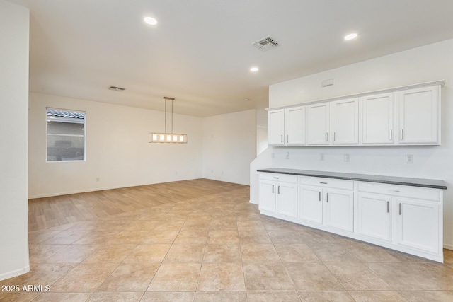 kitchen featuring white cabinets, decorative light fixtures, and light tile patterned flooring