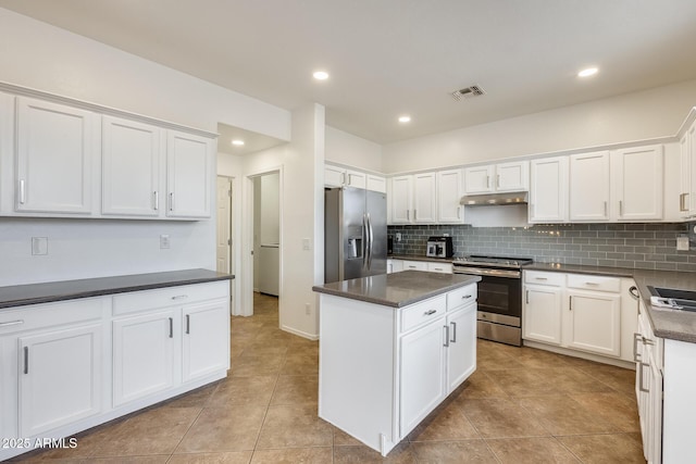 kitchen featuring tasteful backsplash, stainless steel appliances, a kitchen island, white cabinetry, and light tile patterned flooring