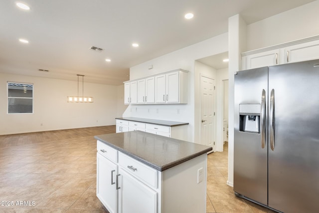 kitchen featuring stainless steel fridge, a kitchen island, pendant lighting, light tile patterned floors, and white cabinetry