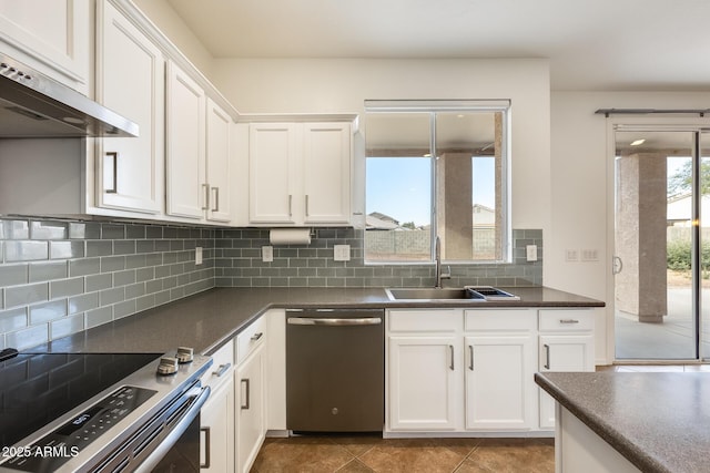 kitchen with white cabinetry, stainless steel appliances, tile patterned floors, extractor fan, and decorative backsplash