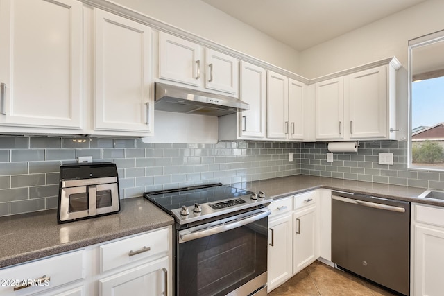 kitchen featuring white cabinets, light tile patterned flooring, backsplash, and appliances with stainless steel finishes