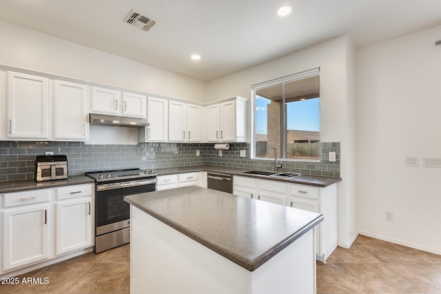 kitchen featuring appliances with stainless steel finishes, backsplash, sink, a center island, and white cabinetry