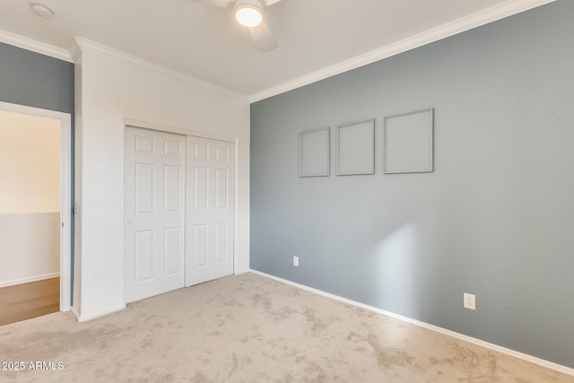 unfurnished bedroom with crown molding, ceiling fan, a closet, and light carpet