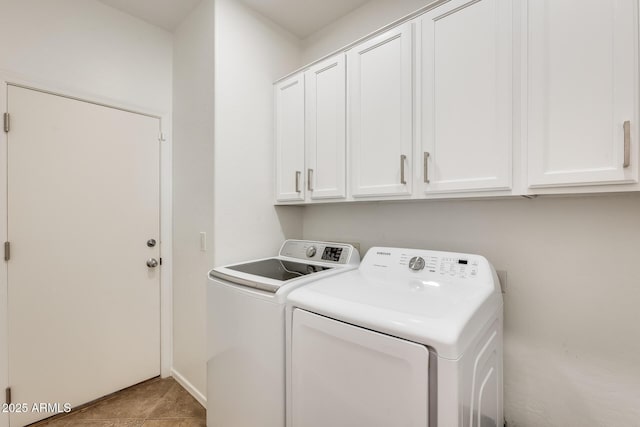 clothes washing area featuring washing machine and dryer, light tile patterned floors, and cabinets