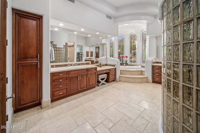 bathroom featuring a relaxing tiled tub and vanity