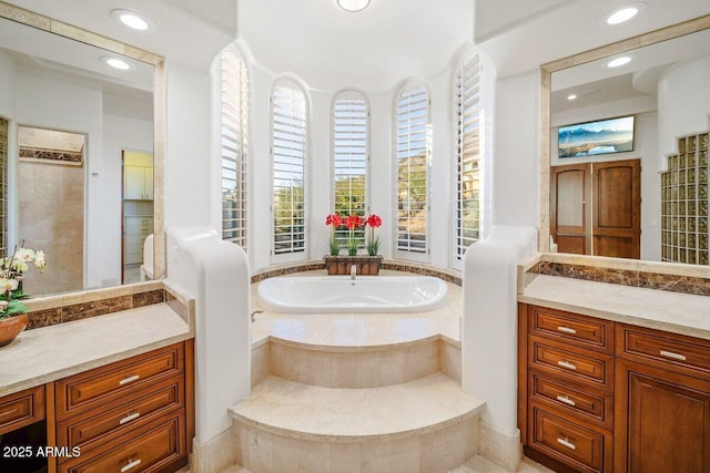 bathroom featuring vanity and tiled tub