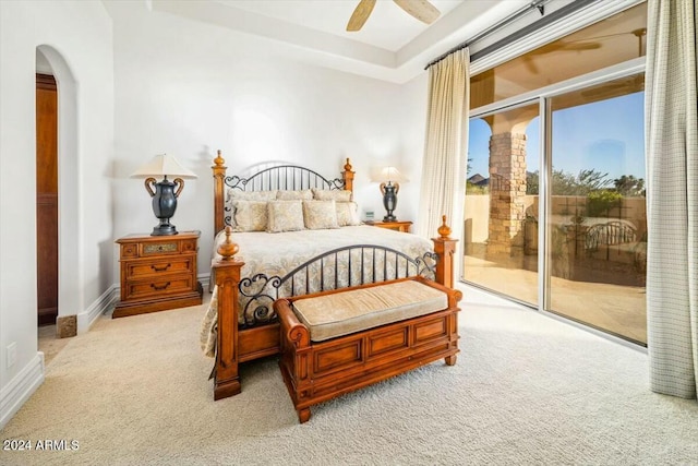 carpeted bedroom with a tray ceiling, access to exterior, and ceiling fan