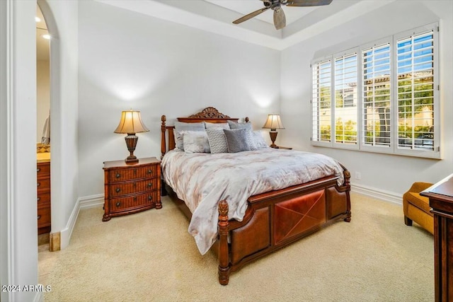 carpeted bedroom featuring a raised ceiling and ceiling fan