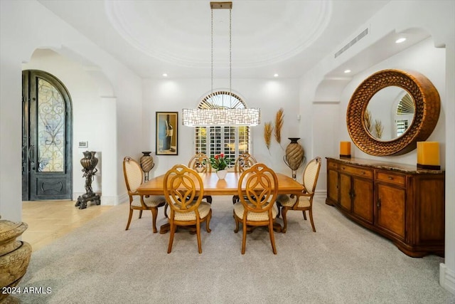 dining room with a raised ceiling and light carpet