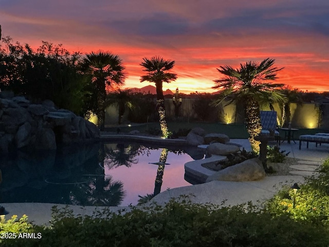 pool at dusk with a patio area