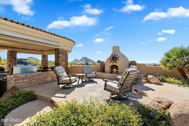 view of patio / terrace featuring an outdoor fireplace and a mountain view