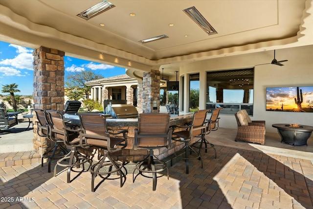 view of patio / terrace featuring ceiling fan, grilling area, exterior bar, and exterior kitchen