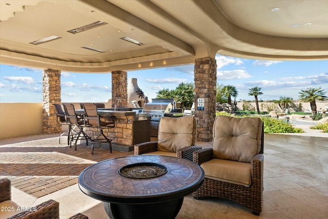 view of patio featuring a bar, an outdoor kitchen, an outdoor fire pit, and area for grilling