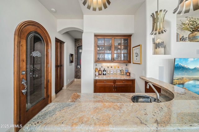 bar featuring light stone countertops and sink