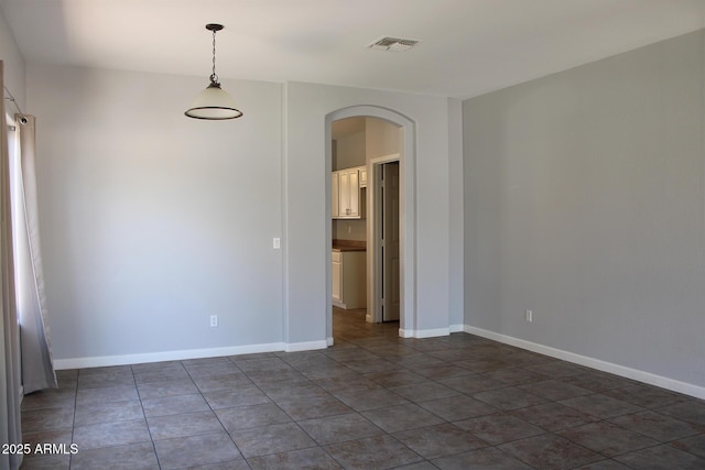 3559 N 143rd Ave, Goodyear, AZ 85395 - empty room featuring arched walkways, dark tile patterned floors, and baseboards