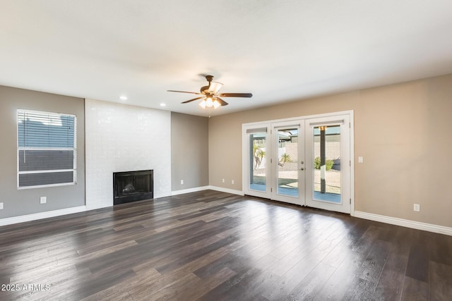 unfurnished living room featuring french doors, a fireplace, dark hardwood / wood-style floors, and ceiling fan