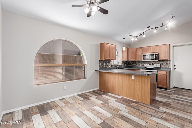 kitchen with a peninsula, light wood-style flooring, tasteful backsplash, and appliances with stainless steel finishes