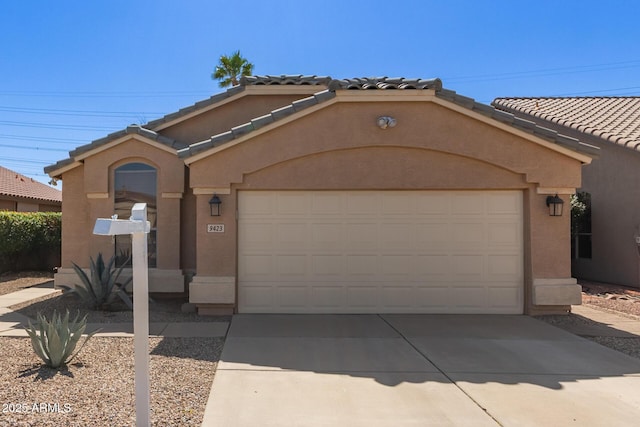 view of front of home featuring a tiled roof, a garage, driveway, and stucco siding