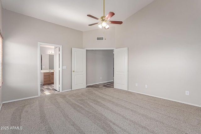 unfurnished bedroom with visible vents, connected bathroom, baseboards, carpet, and high vaulted ceiling