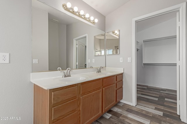 bathroom featuring double vanity, wood finished floors, baseboards, and a sink