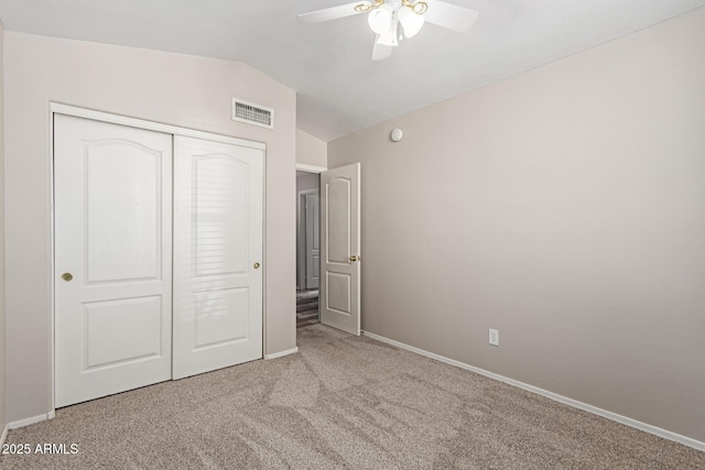 unfurnished bedroom with visible vents, lofted ceiling, a closet, carpet floors, and baseboards