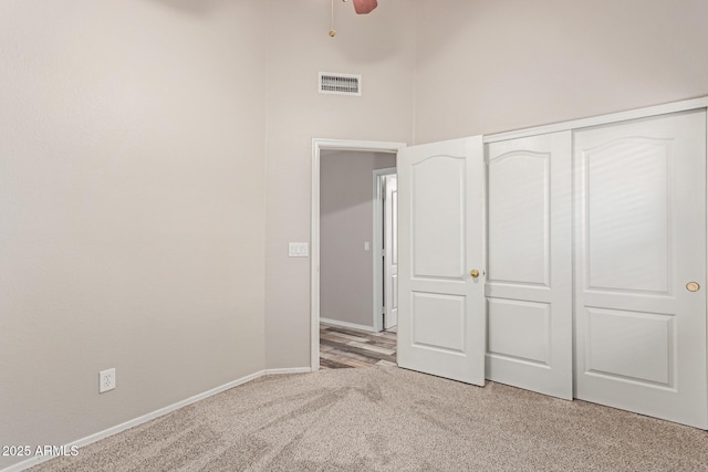 unfurnished bedroom with light colored carpet, visible vents, a closet, and baseboards