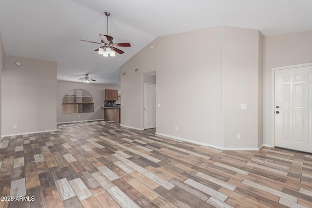 unfurnished living room featuring light wood finished floors, visible vents, a ceiling fan, and vaulted ceiling