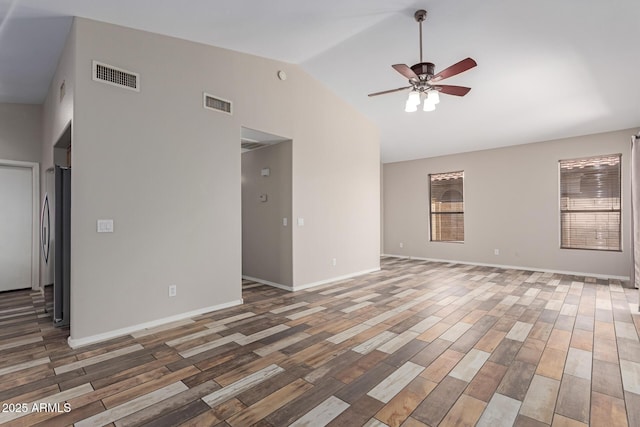 empty room featuring a ceiling fan, vaulted ceiling, wood finished floors, and visible vents