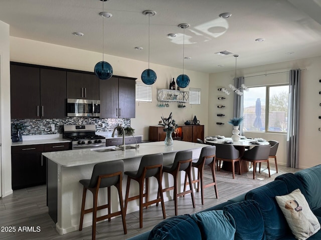 kitchen with stainless steel appliances, a sink, visible vents, a kitchen breakfast bar, and open floor plan