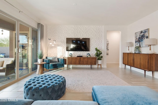 living room featuring wallpapered walls, an accent wall, baseboards, and wood finished floors