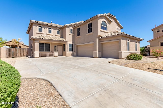 mediterranean / spanish home with fence, stucco siding, concrete driveway, a garage, and a tile roof