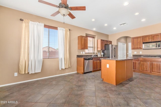 kitchen with a wealth of natural light, arched walkways, appliances with stainless steel finishes, and a kitchen island