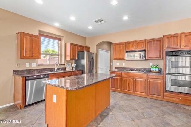 kitchen with visible vents, a center island, dark stone counters, appliances with stainless steel finishes, and a sink