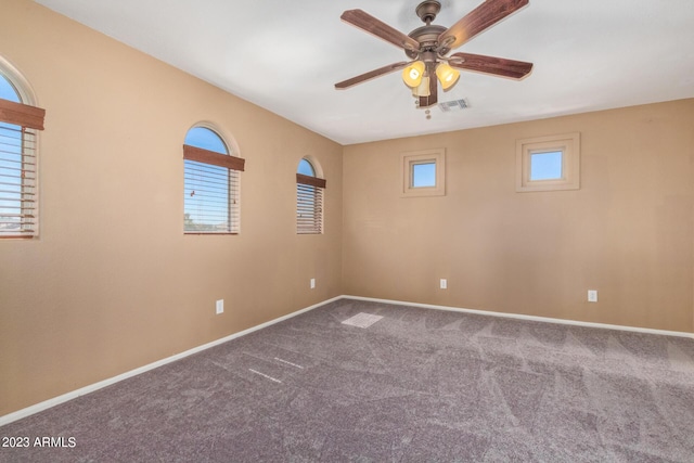 empty room featuring a wealth of natural light, visible vents, baseboards, and carpet