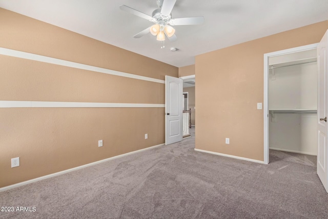 unfurnished bedroom featuring a walk in closet, baseboards, a closet, and carpet flooring