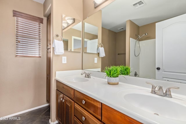 bathroom with a sink, visible vents, double vanity, and tile patterned flooring