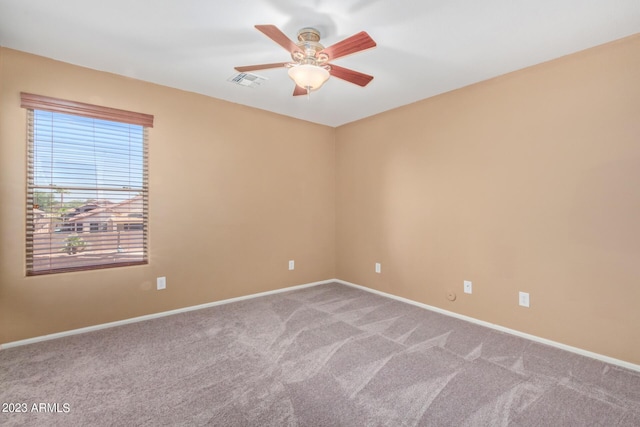 carpeted empty room featuring baseboards, visible vents, and ceiling fan