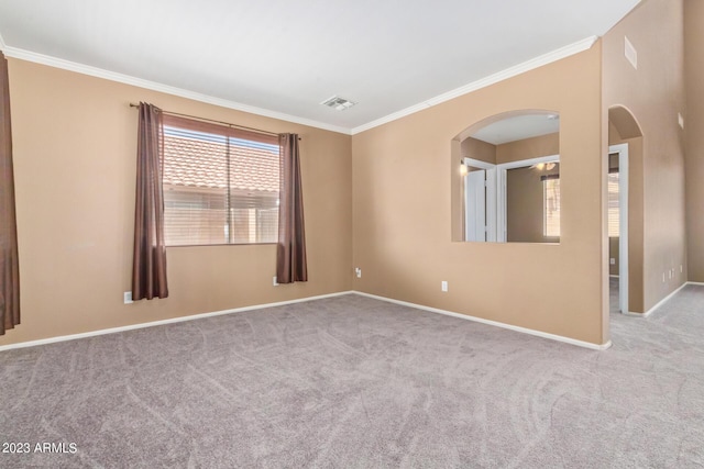 carpeted spare room featuring crown molding, arched walkways, visible vents, and baseboards