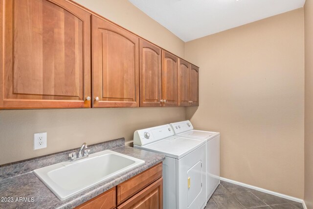 washroom featuring washer and dryer, cabinet space, baseboards, and a sink