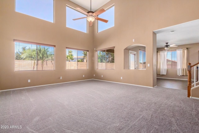 empty room with carpet flooring, ceiling fan, stairway, and baseboards