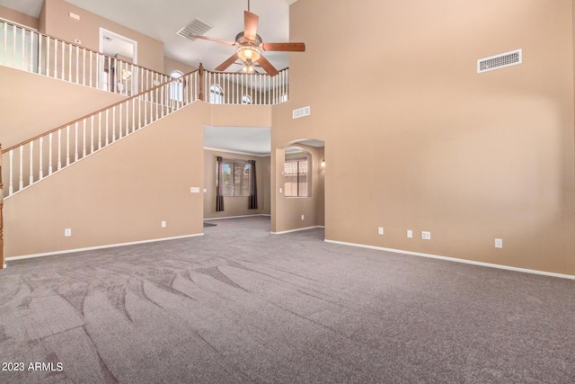 unfurnished living room featuring baseboards, arched walkways, carpet, and ceiling fan