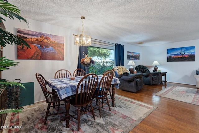 dining area featuring hardwood / wood-style flooring, a textured ceiling, and an inviting chandelier